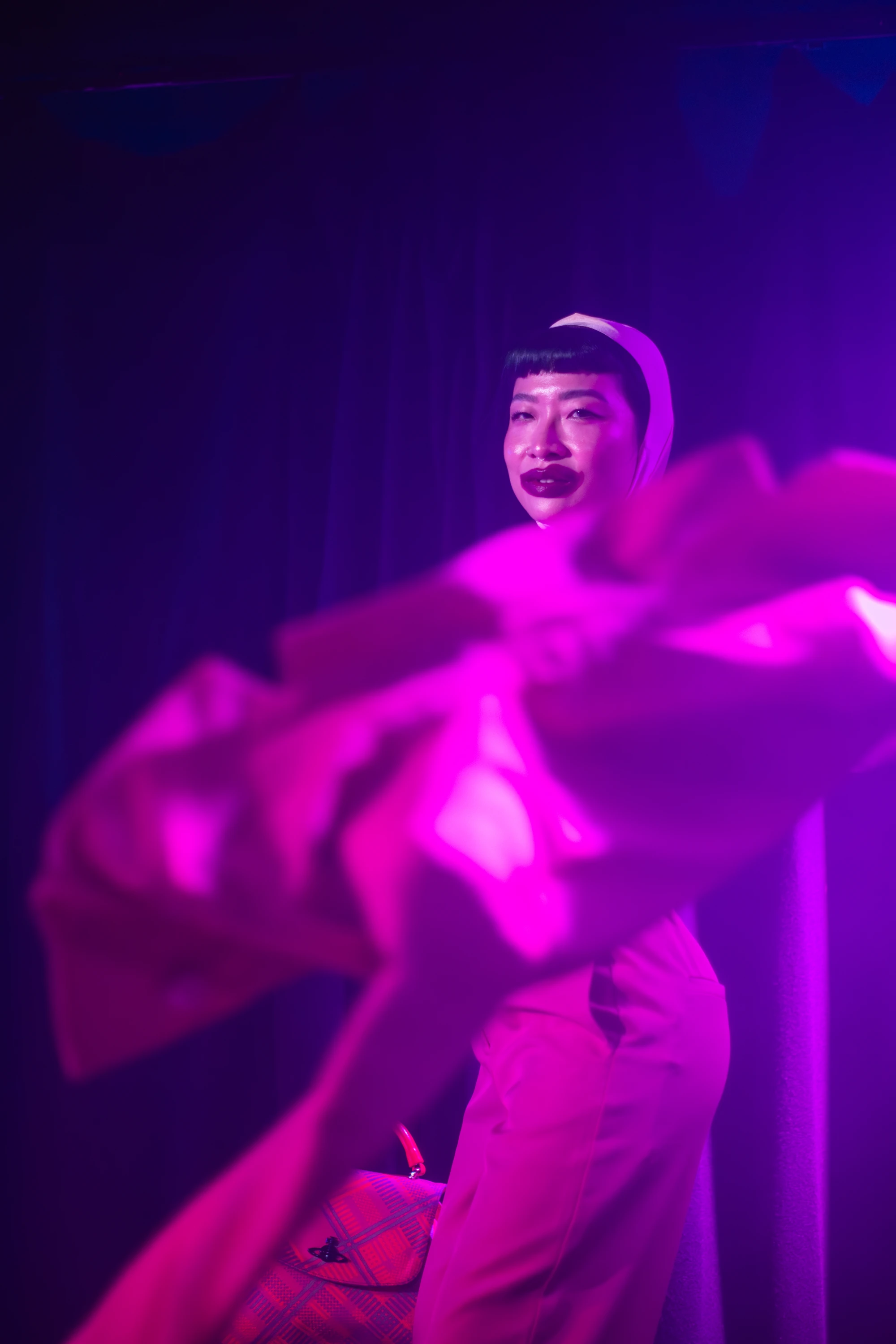 a woman throws her suit jacket at the camer, she has lipstick all over her mouth.