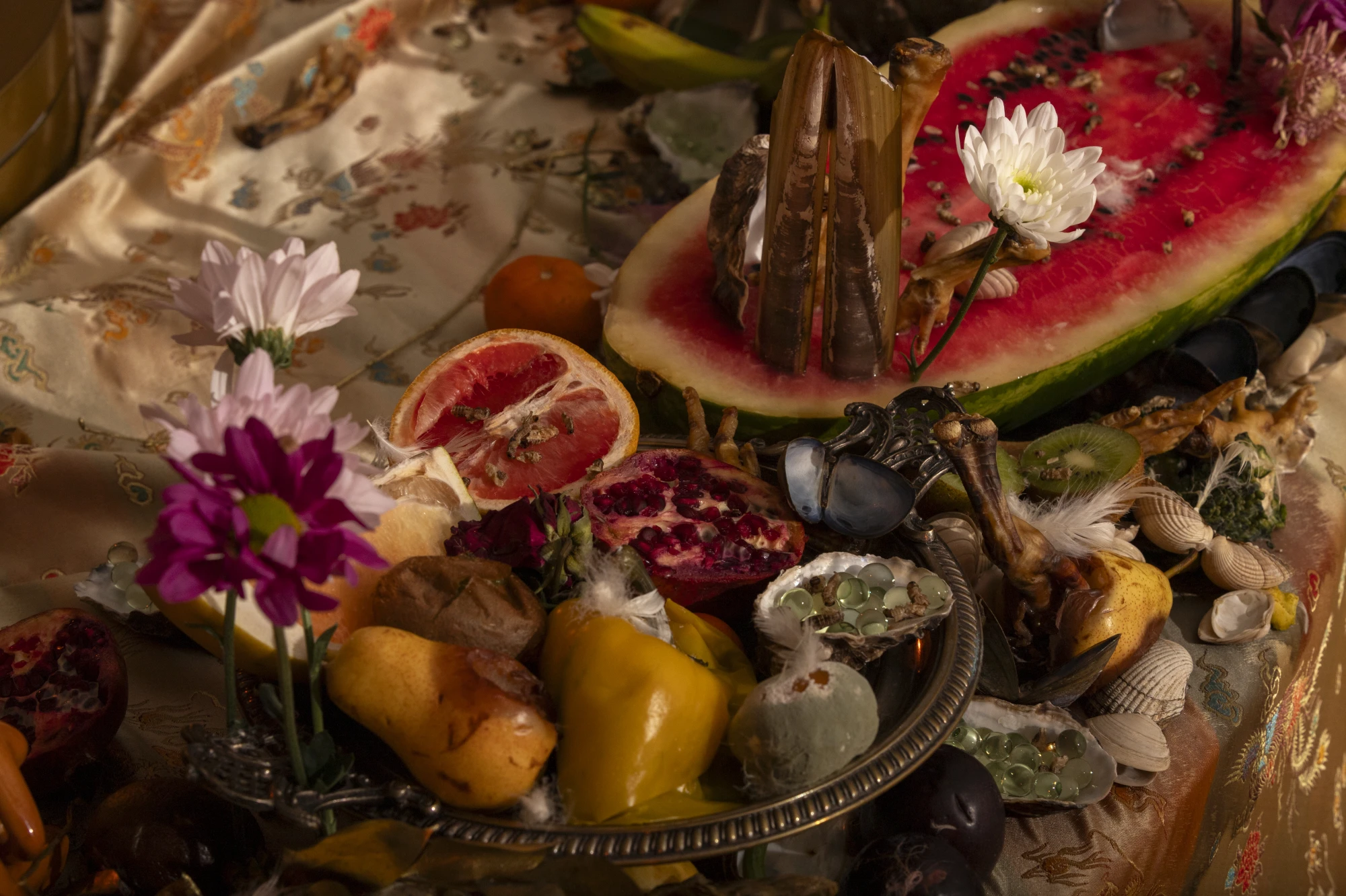 installation documentation of rotting fruit, flowers and crusteasans on top of emboidered 'oriental' style fabric.