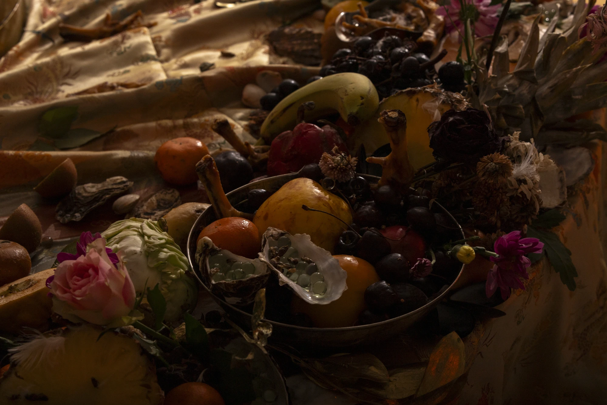 installation documentation of rotting fruit, flowers and crusteasans on top of emboidered 'oriental' style fabric.