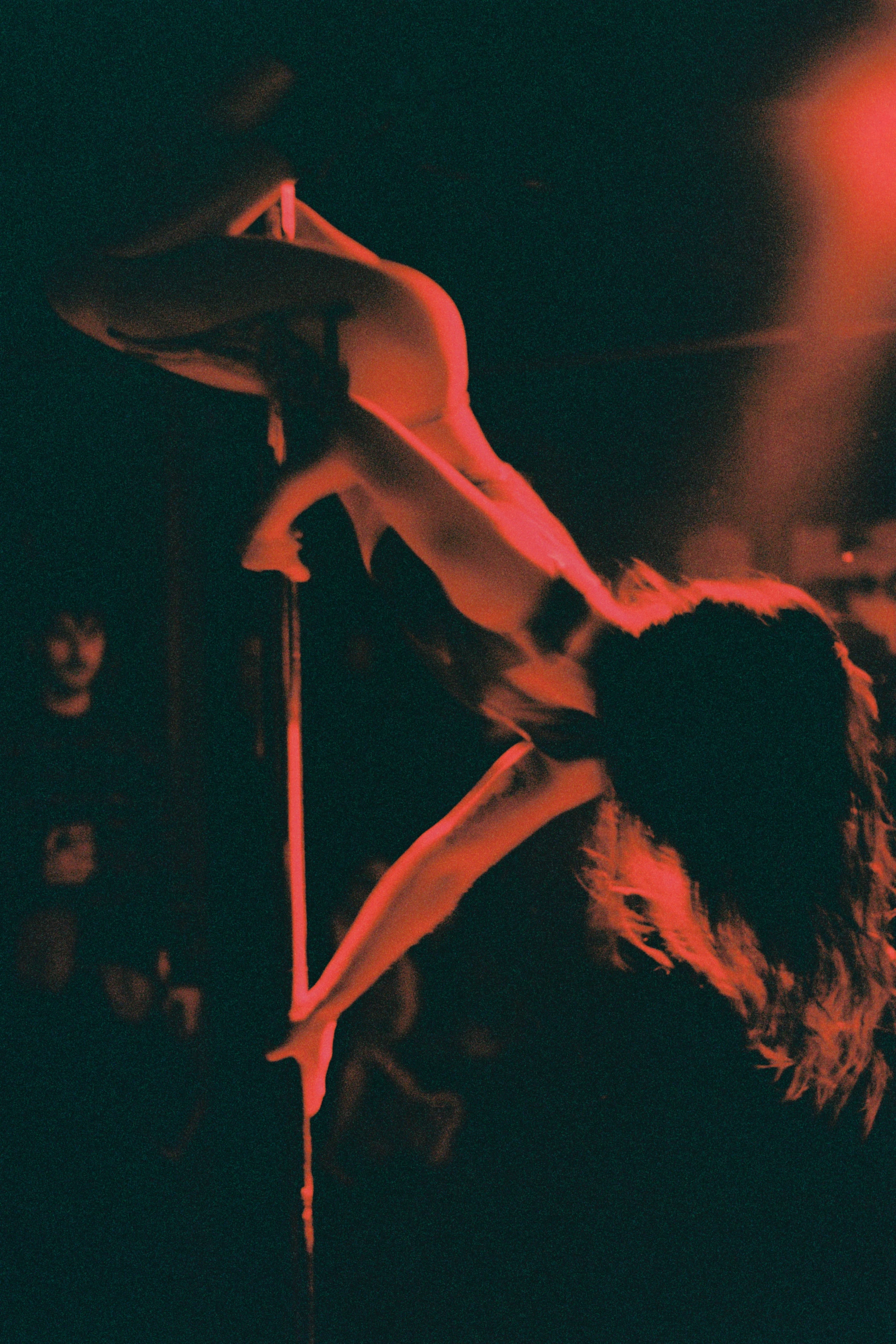 a woman is upside down on a pole under a red light.