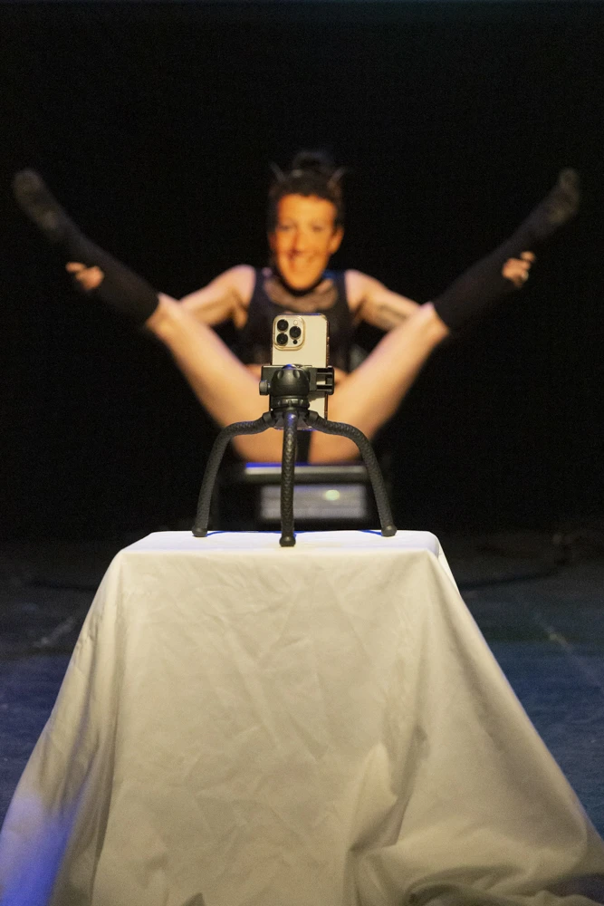 a woman wearing black hoodie and sweatpants performs as Mark Zuckerberg.