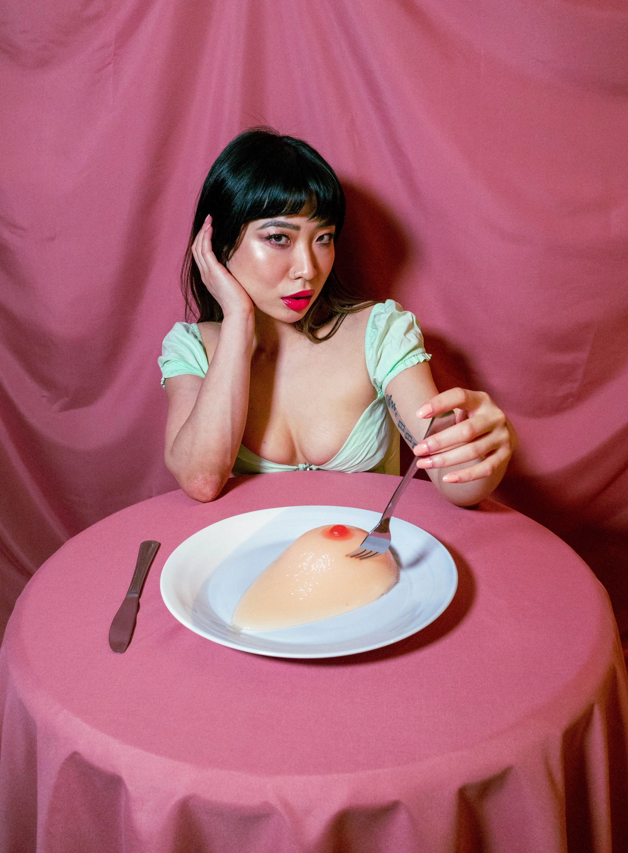 a woman in a green corset is eating a breast on a plate.