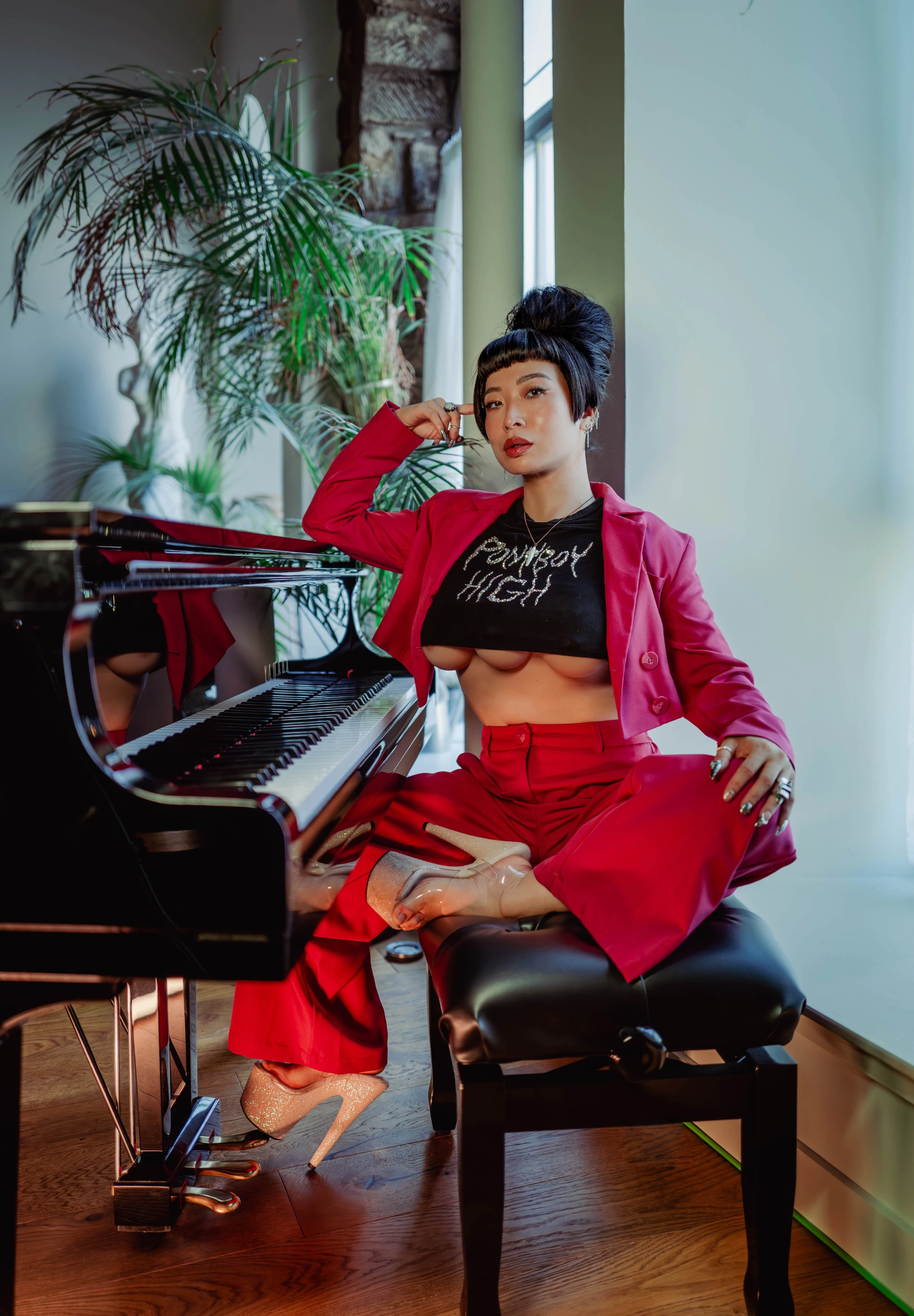 a woman with three boobs is wearing a pink suit and sitting at a baby grand piano.