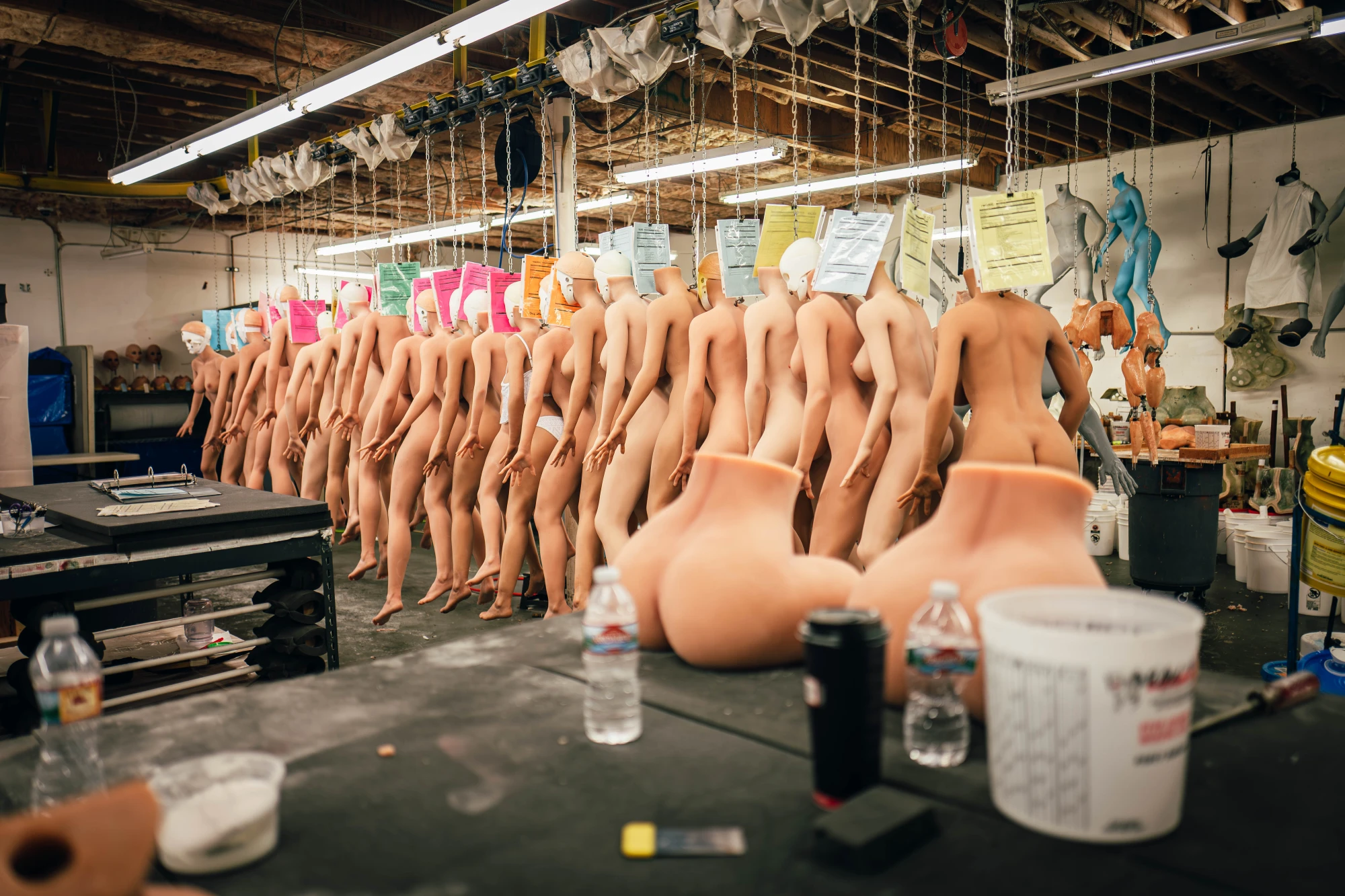 silicone doll bodies are hanging in a factory.