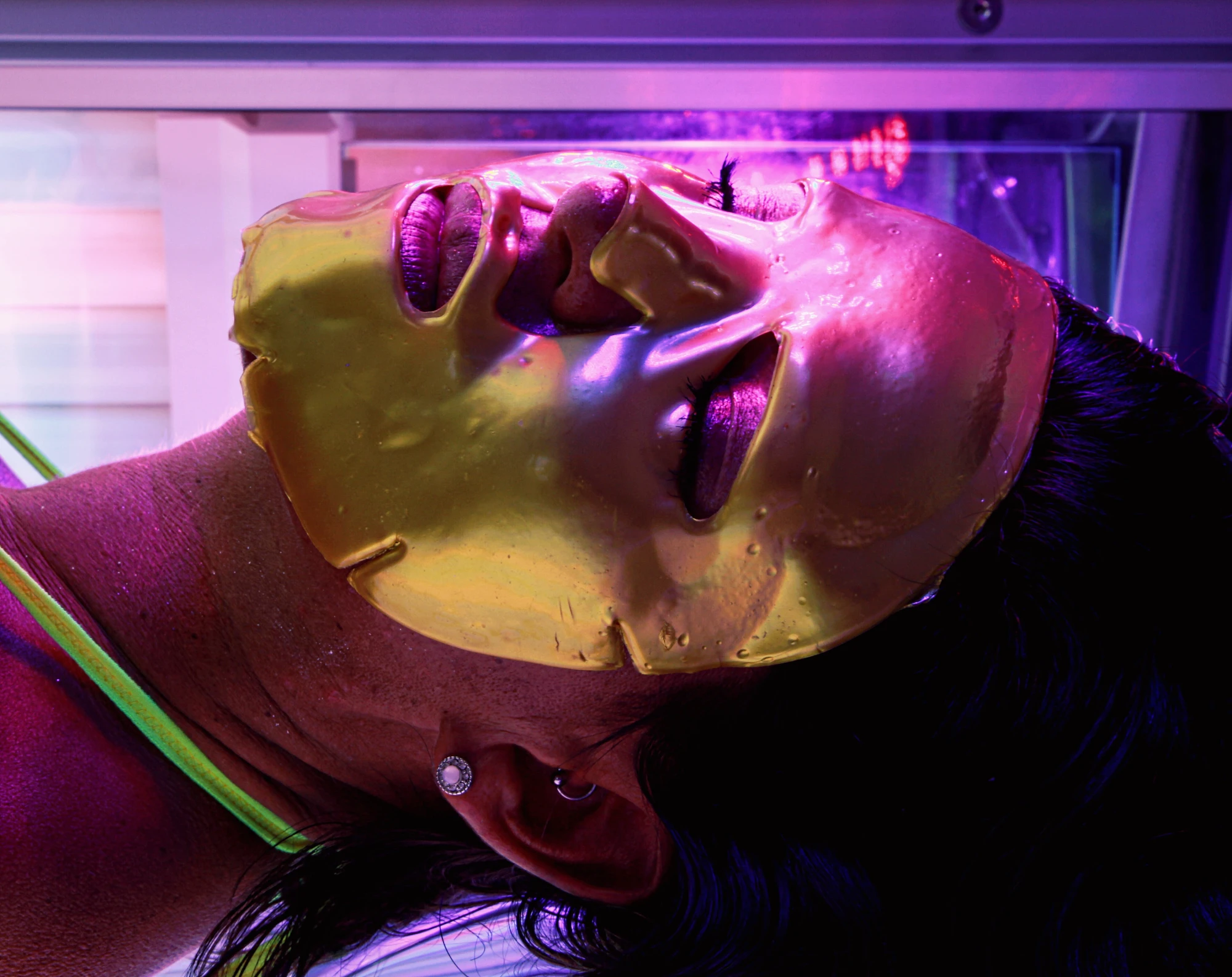 a close up of a woman's face, wearing a gold face mask.