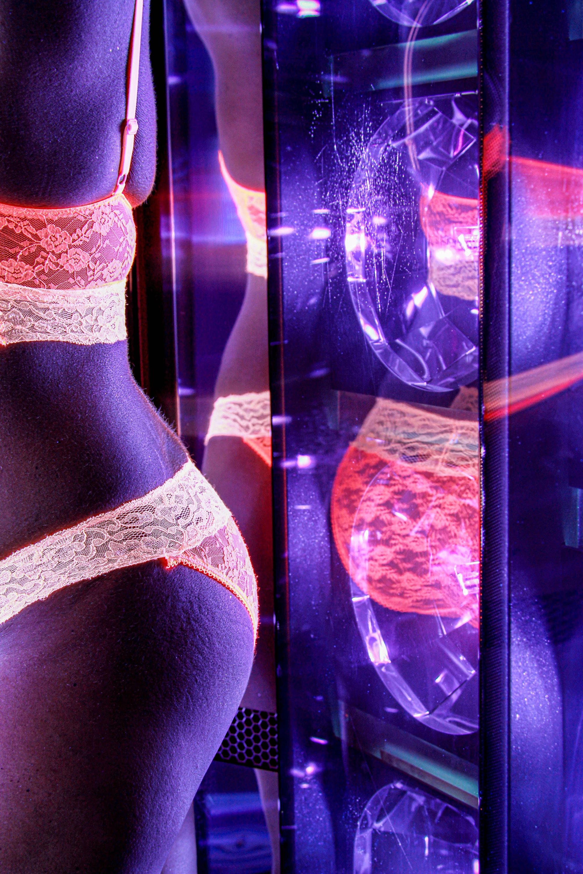 a woman wearing bright lingerie is in a tanning booth.