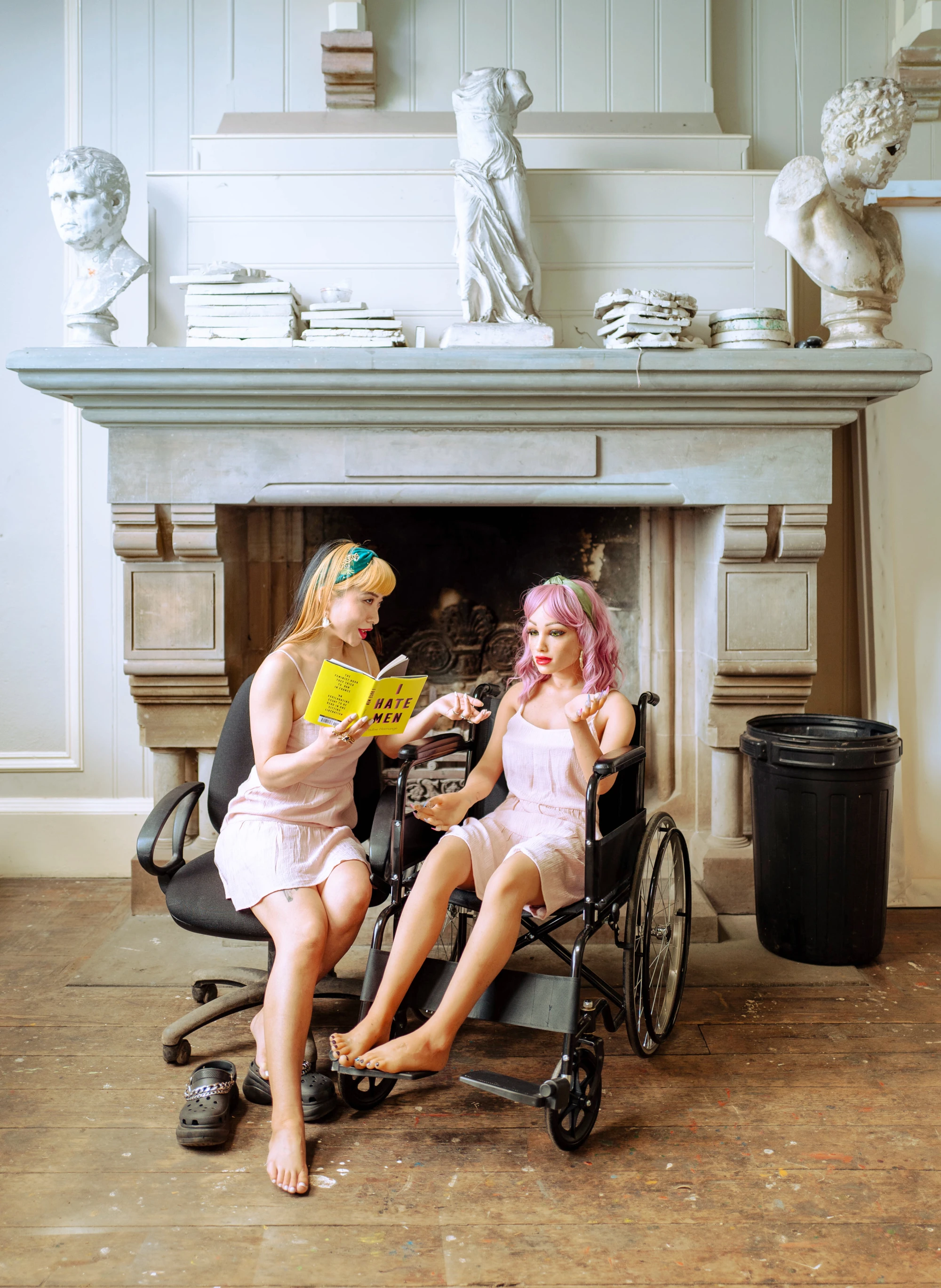 a woman and a silicone love doll is reading a book together called 'I hate men'.