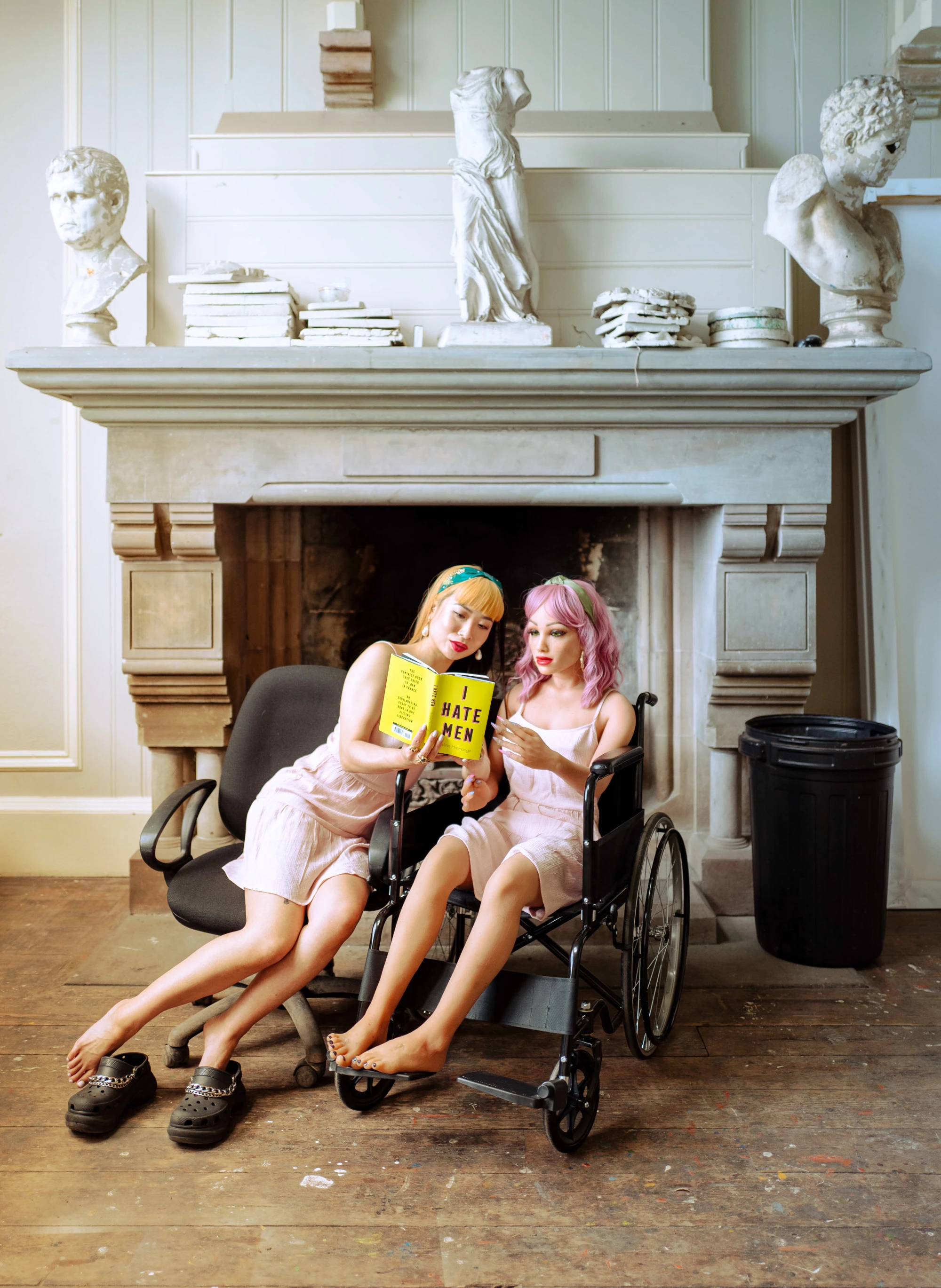 a woman and a silicone love doll is reading a book together called 'I hate men'.