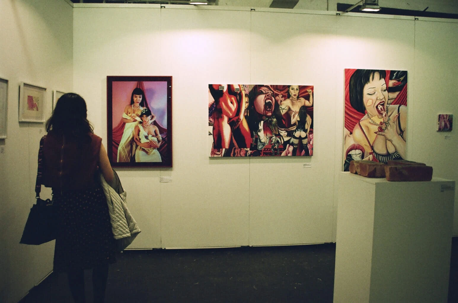 a visitor looks at photogaphs and paintings at an exhibition.